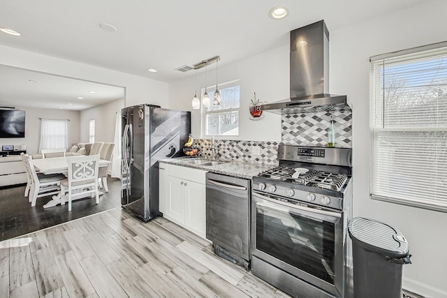 7715 W Patterson Ave, Chicago, IL 60634 - kitchen with appliances with stainless steel finishes, wall chimney range hood, a sink, light wood finished floors, and white cabinets