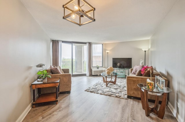 living room featuring wood finished floors, expansive windows, a chandelier, and baseboards