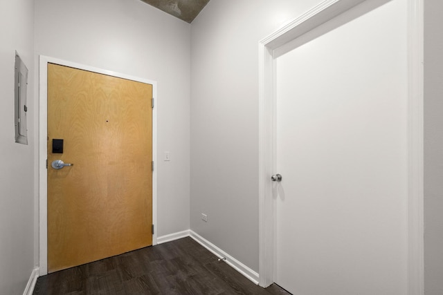 doorway to outside with dark wood-style flooring, electric panel, and baseboards