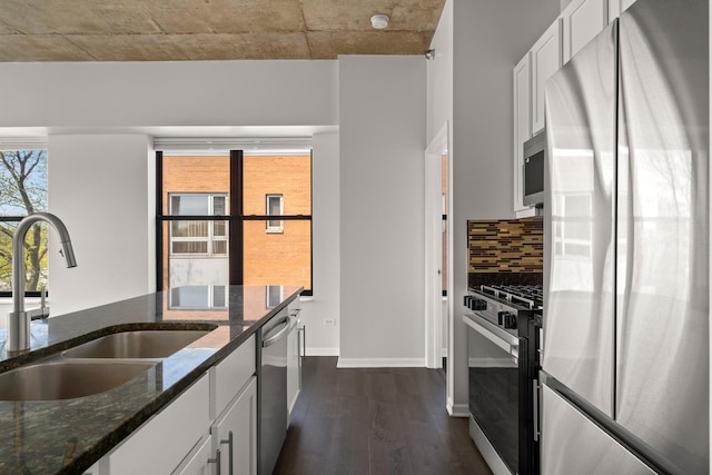 kitchen with stainless steel appliances, a sink, dark wood finished floors, tasteful backsplash, and white cabinetry