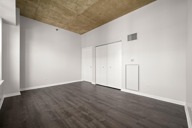 unfurnished bedroom featuring dark wood-style flooring, baseboards, and a closet