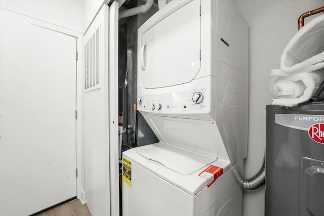 laundry room with stacked washing machine and dryer and water heater