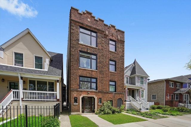 townhome / multi-family property with brick siding, a porch, a fenced front yard, and stairs