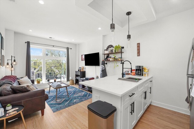 kitchen featuring a sink, open floor plan, light wood-style flooring, white cabinetry, and recessed lighting