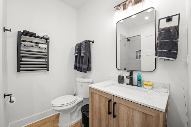 bathroom with wood finished floors, toilet, baseboards, radiator, and vanity