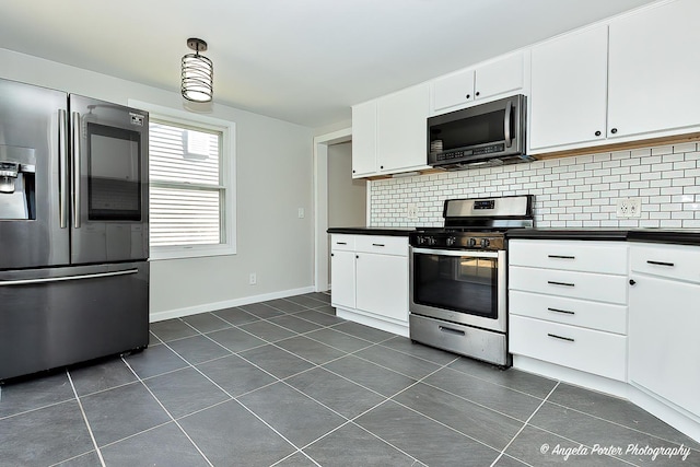 5305 N Highland Dr, Mchenry, IL 60050 - kitchen featuring appliances with stainless steel finishes, dark countertops, dark tile patterned floors, decorative backsplash, and baseboards