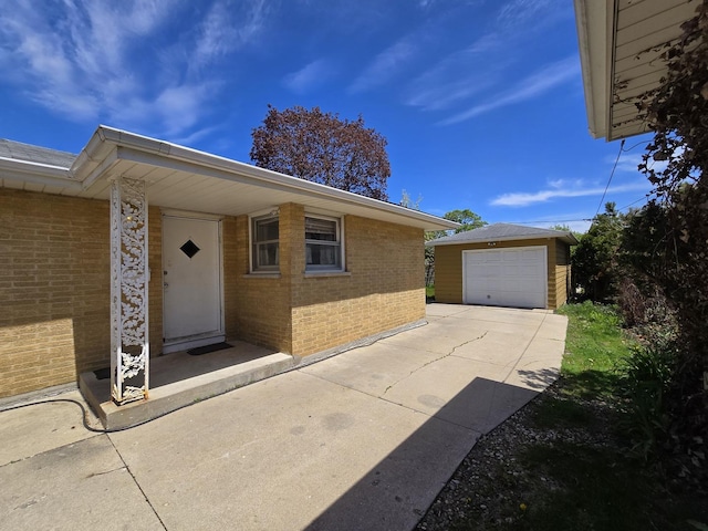 doorway to property with brick siding, a detached garage, and driveway
