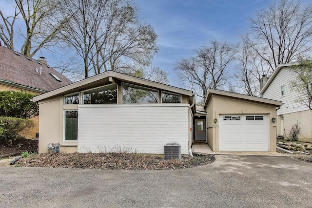 523 Green Bay Rd, Highland Park, IL 60035 - view of side of property featuring an attached garage, asphalt driveway, stucco siding, and central AC