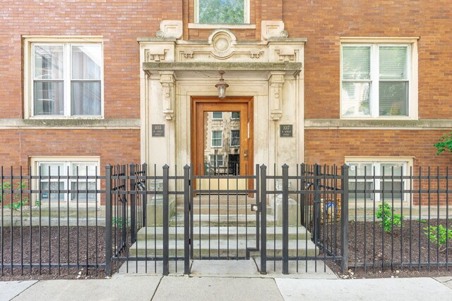 property entrance featuring brick siding, fence, and a gate