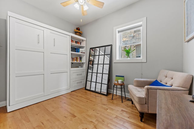 living area featuring light wood-type flooring, baseboards, and ceiling fan