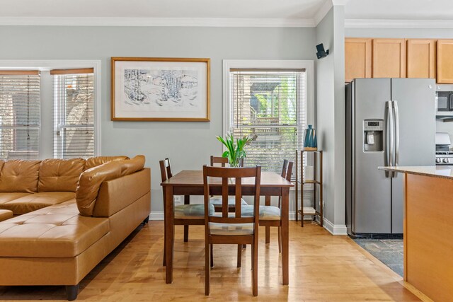 dining room with light wood-type flooring, baseboards, and crown molding