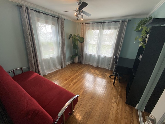 living area with wood finished floors, ornamental molding, and ceiling fan