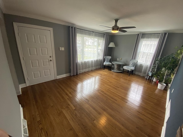 foyer entrance featuring crown molding, wood finished floors, healthy amount of natural light, a ceiling fan, and baseboards