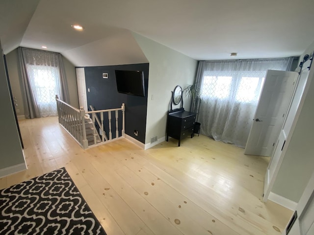 additional living space with lofted ceiling, light wood-style flooring, and baseboards