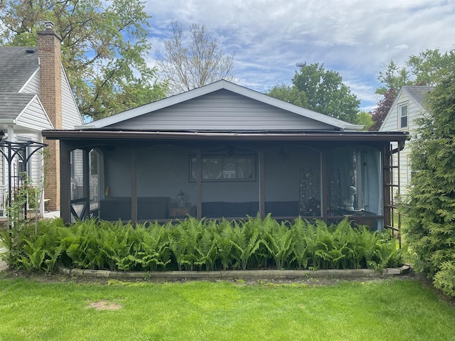 rear view of house with a lawn and a sunroom