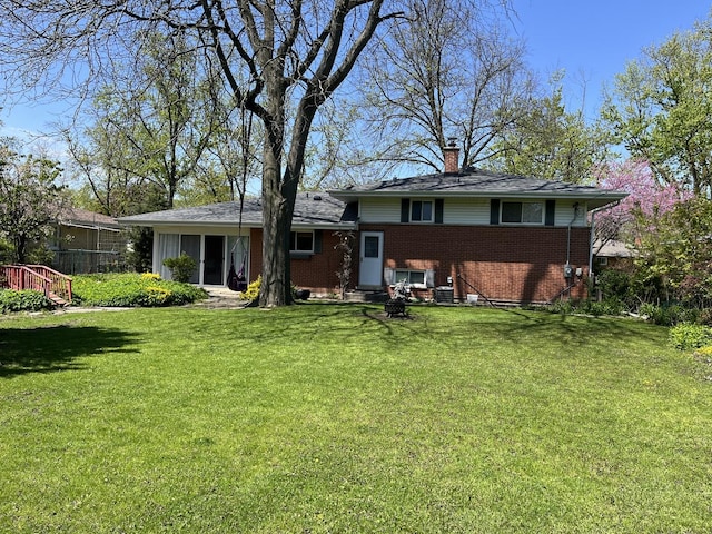 rear view of house featuring brick siding, a lawn, and a chimney