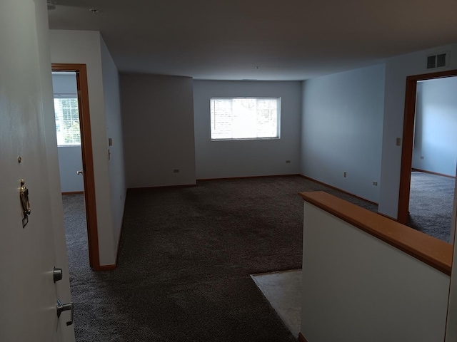 spare room featuring carpet floors, plenty of natural light, and baseboards