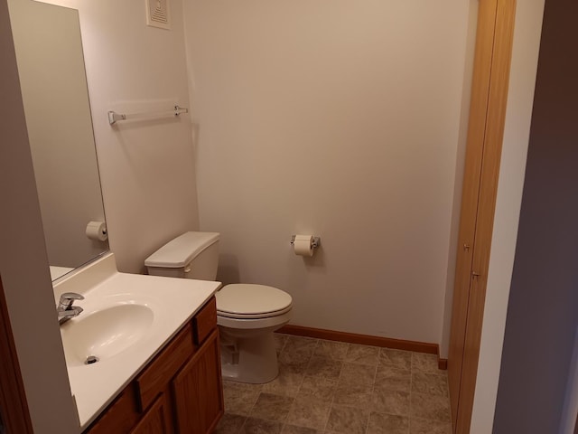 bathroom featuring toilet, vanity, and baseboards