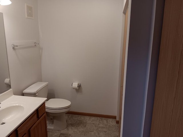 bathroom featuring toilet, vanity, and baseboards