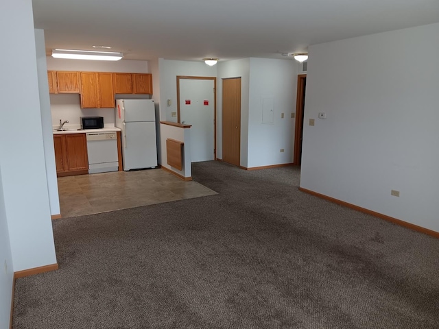kitchen featuring white appliances, a sink, baseboards, and light colored carpet