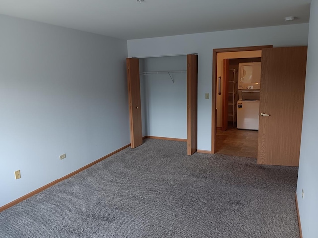 unfurnished bedroom featuring estacked washer and dryer, carpet, a closet, and baseboards