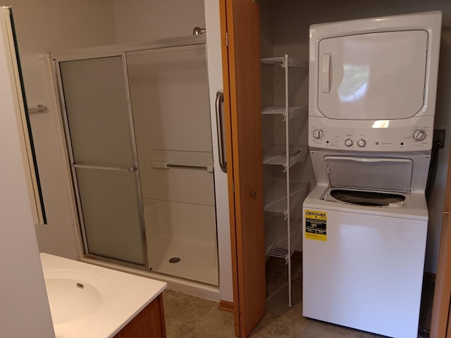 bathroom with stacked washing machine and dryer, a stall shower, and vanity