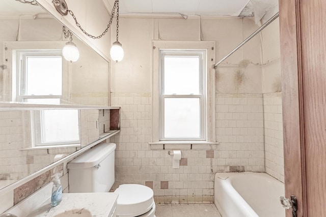 bathroom with tile walls, toilet, vanity, tile patterned floors, and a wainscoted wall
