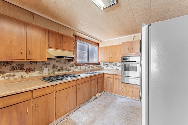 kitchen featuring appliances with stainless steel finishes, a warming drawer, a sink, under cabinet range hood, and light countertops