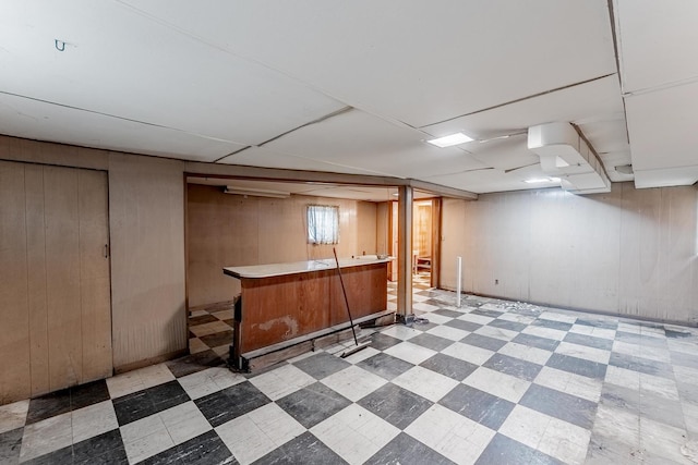 below grade area with light floors, a dry bar, and wood walls
