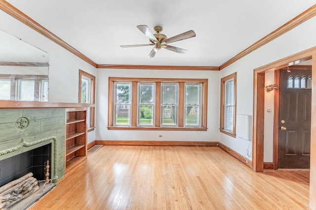 unfurnished living room featuring baseboards, a tile fireplace, light wood finished floors, a ceiling fan, and ornamental molding