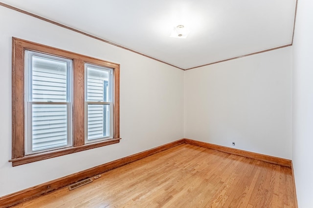unfurnished room with light wood-type flooring, baseboards, and crown molding