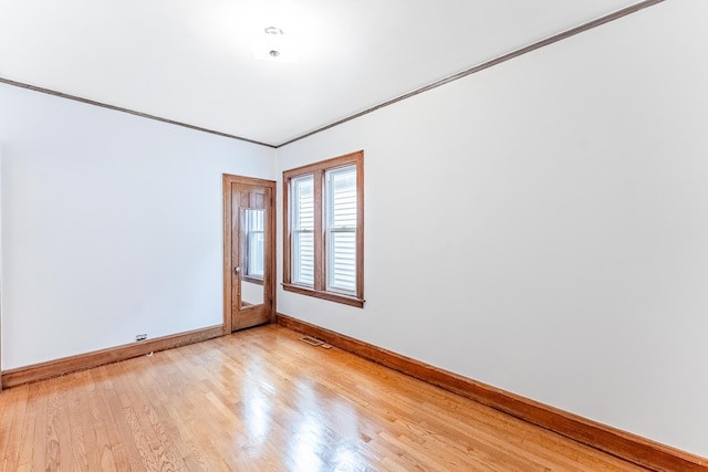 empty room with baseboards, light wood-style floors, and ornamental molding