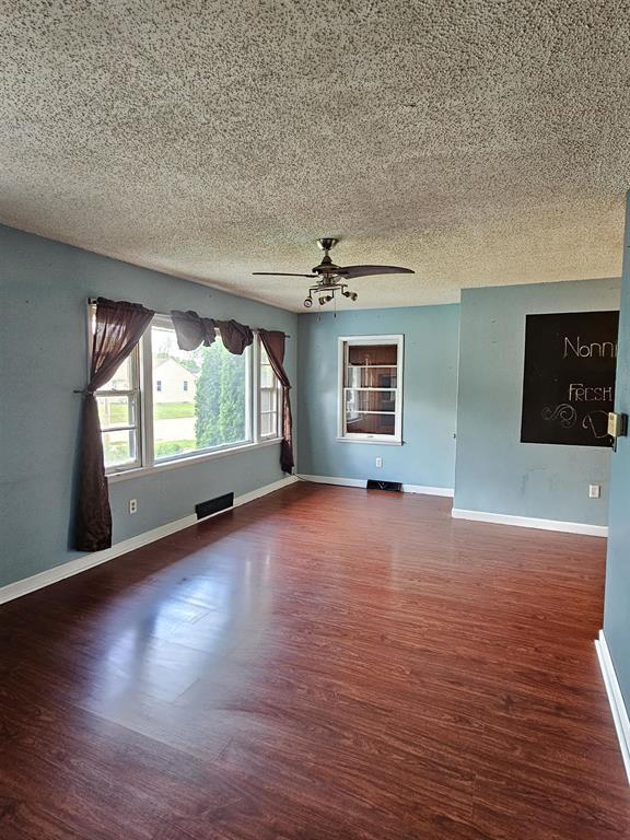 506 S 8th St, Oregon, IL 61061 - empty room featuring wood finished floors, a textured ceiling, baseboards, and a ceiling fan