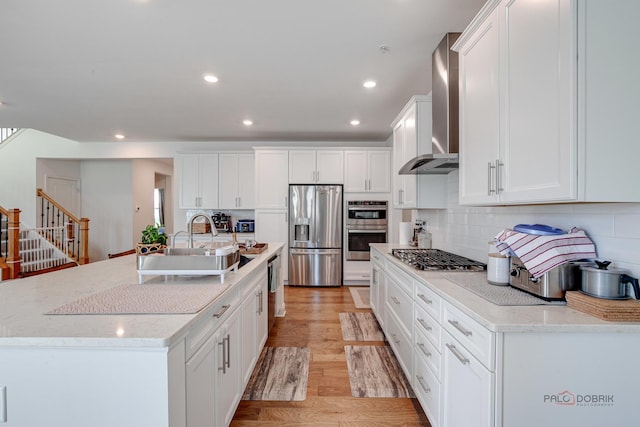 1027 Button Bush St, South Elgin, IL 60177 - kitchen featuring appliances with stainless steel finishes, wall chimney range hood, white cabinets, tasteful backsplash, and light wood finished floors