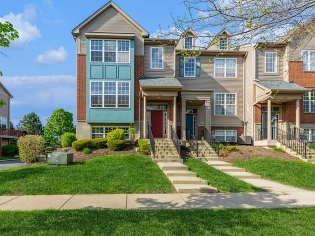 townhome / multi-family property with a front lawn, brick siding, and central AC unit