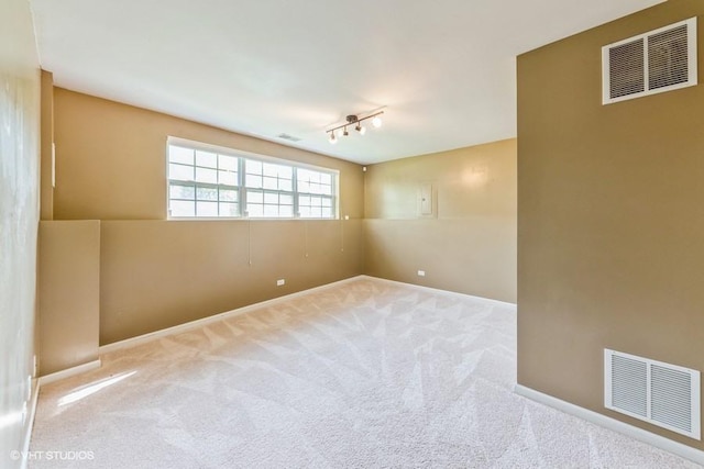 carpeted empty room featuring baseboards and rail lighting