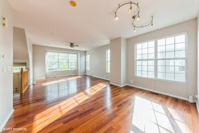 unfurnished living room featuring wood finished floors, baseboards, and ceiling fan