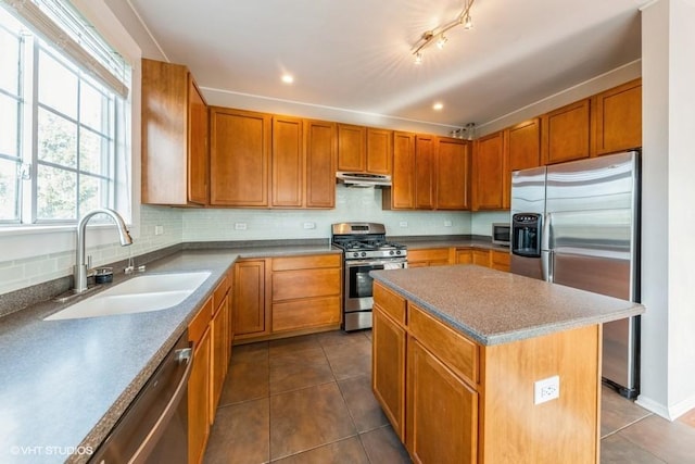 kitchen with stainless steel appliances, a sink, dark tile patterned flooring, backsplash, and recessed lighting