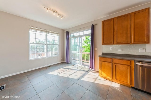 kitchen featuring stainless steel dishwasher, brown cabinetry, dark countertops, and baseboards