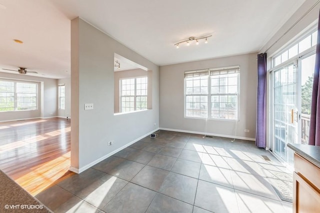 tiled empty room with baseboards and a ceiling fan