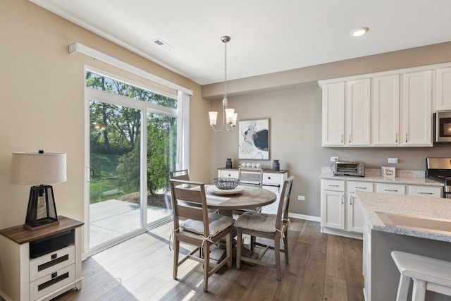 dining area with dark wood-type flooring, a chandelier, baseboards, and recessed lighting