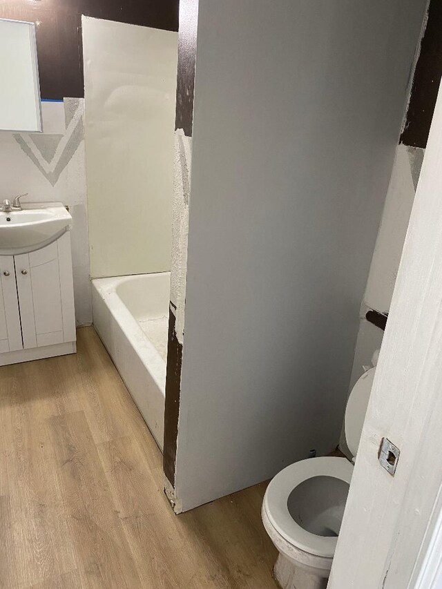 11809 S Lafayette Ave, Chicago, IL 60628 - bathroom with wood finished floors, toilet, a bathtub, and vanity