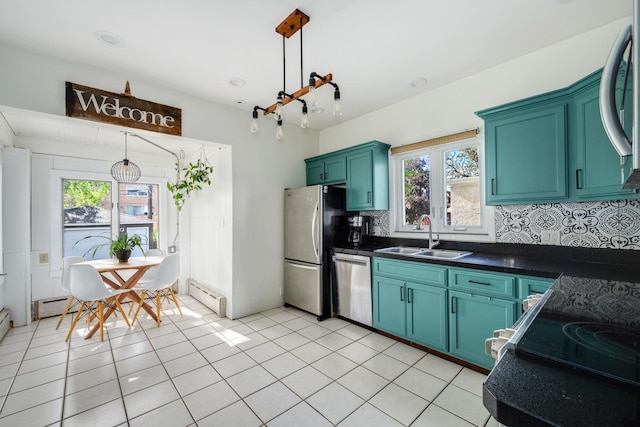 kitchen with a sink, stainless steel appliances, baseboard heating, dark countertops, and tasteful backsplash