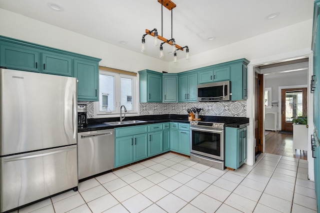 kitchen featuring appliances with stainless steel finishes, a sink, dark countertops, and healthy amount of natural light