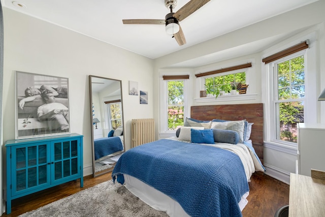 bedroom featuring radiator heating unit, wood finished floors, ceiling fan, and baseboards