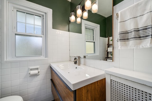 bathroom featuring tile walls, vanity, and toilet