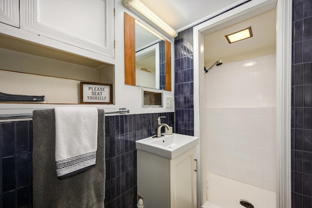 full bathroom with tile walls, a shower stall, and vanity