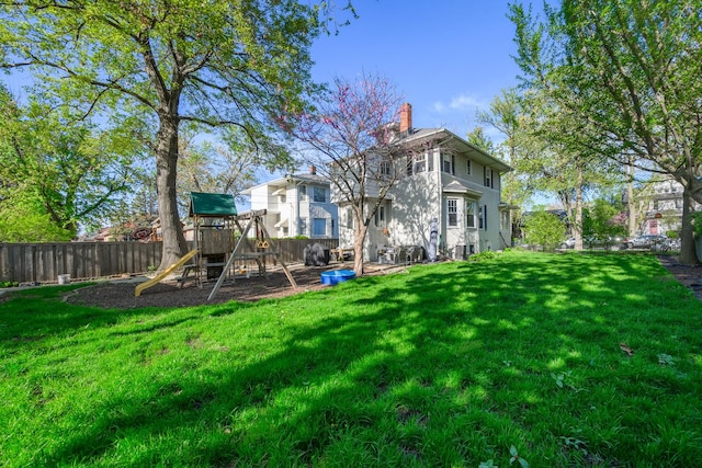 rear view of house featuring a playground and a chimney