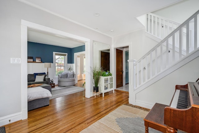 foyer entrance with wood finished floors, stairway, baseboards, and crown molding