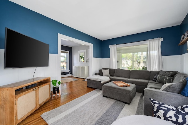 living room with a wainscoted wall, wood finished floors, and a decorative wall